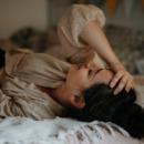 Vrouw ligt op bed door menstruatiepijn en voelt zich eenzaam.