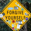 een verkeersbord met daarop de tekst 'forgive yourself'