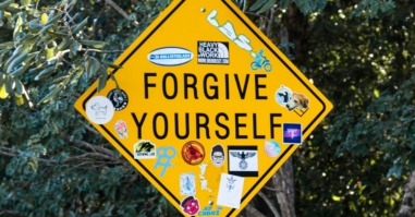 een verkeersbord met daarop de tekst 'forgive yourself'