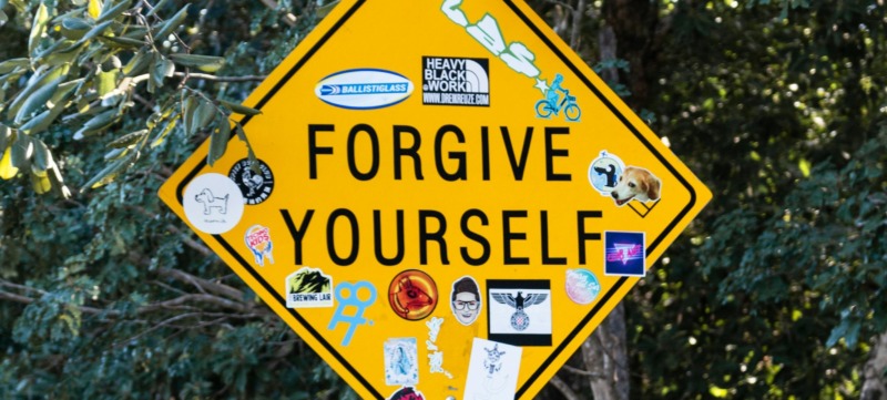 een verkeersbord met daarop de tekst 'forgive yourself'