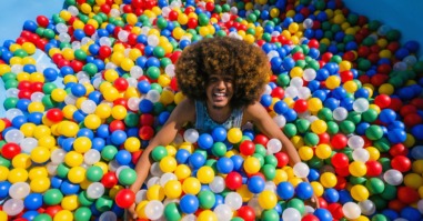 een man ligt in de ballenbak en streeft een rommelig en speels leven na