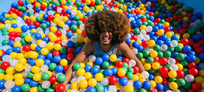 een man ligt in de ballenbak en streeft een rommelig en speels leven na