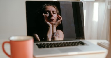 vrouw zit voor haar laptop en denkt te veel en doet niks