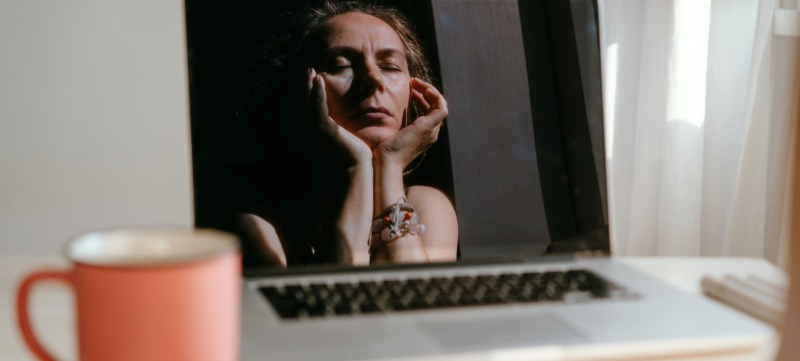 vrouw zit voor haar laptop en denkt te veel en doet niks