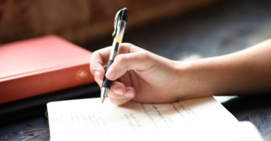 persoon schrijft met een pen haar gedachten op in een boekje