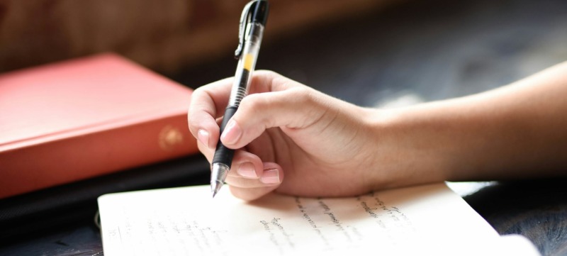 persoon schrijft met een pen haar gedachten op in een boekje