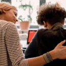 Vrouw legt een hand op de rug van een jongen om hem gerust te stellen.