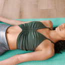 Vrouw ligt op een yogamat en doet yoga nidra