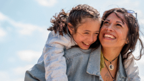 Dochter lachend op de rug bij haar moeder