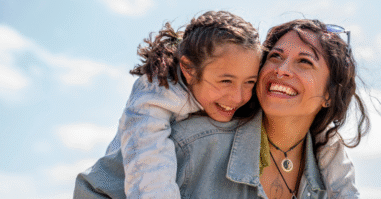 Dochter lachend op de rug bij haar moeder