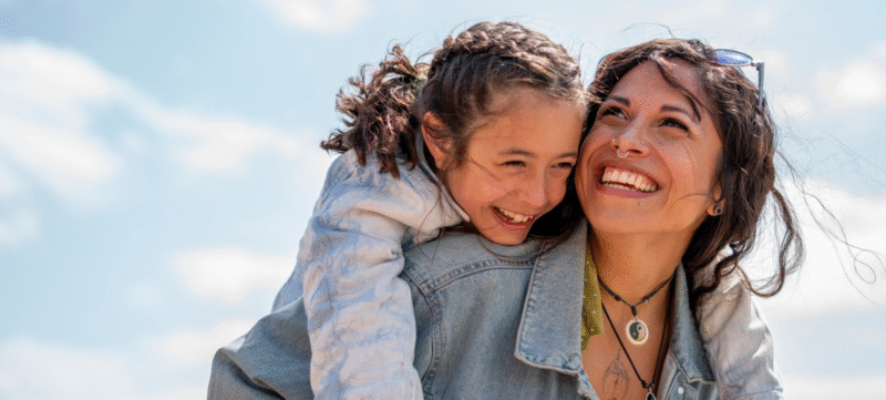 Dochter lachend op de rug bij haar moeder