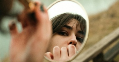 vrouw kijkt naar zichzelf in de spiegel