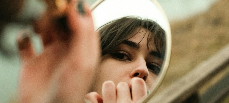 vrouw kijkt naar zichzelf in de spiegel