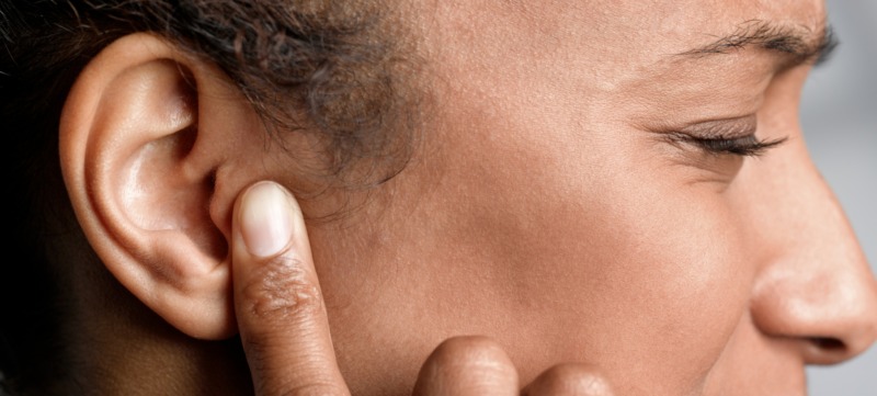 vrouw houdt handen over haar oren tegen de piep in haar oren