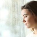 Vrouw kijkt uit het raam met een leegte in haar blik