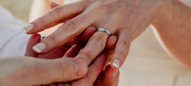 man doet trouwring om de vinger van partner