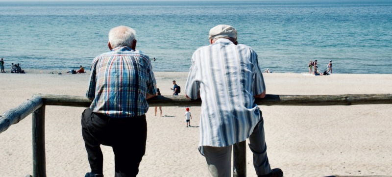 twee mannen staan met elkaar te praten en roddelen over andere mensen