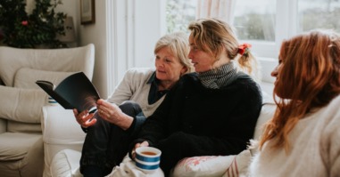 drie vrouwen zitten op een bank en vertellen elkaar over de familie door elkaar vragen te stellen
