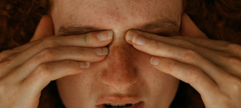 vrouw heeft last van migraine en grijpt naar haar hoofd