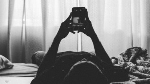 persoon ligt op bed en googlet naar kenmerken van diagnose