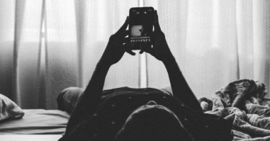 persoon ligt op bed en googlet naar kenmerken van diagnose