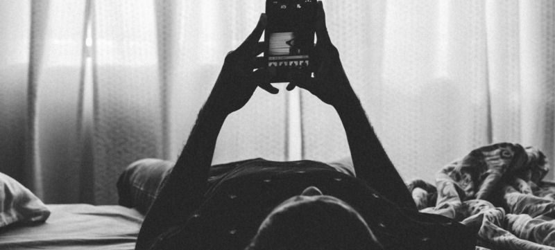 persoon ligt op bed en googlet naar kenmerken van diagnose