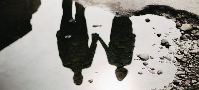 weerspiegeling in een plas van twee mensen in een relatie wat symbool staat voor een relatie die verwaterd