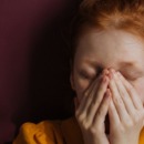 Vrouw met handen voor haar gezicht door angst