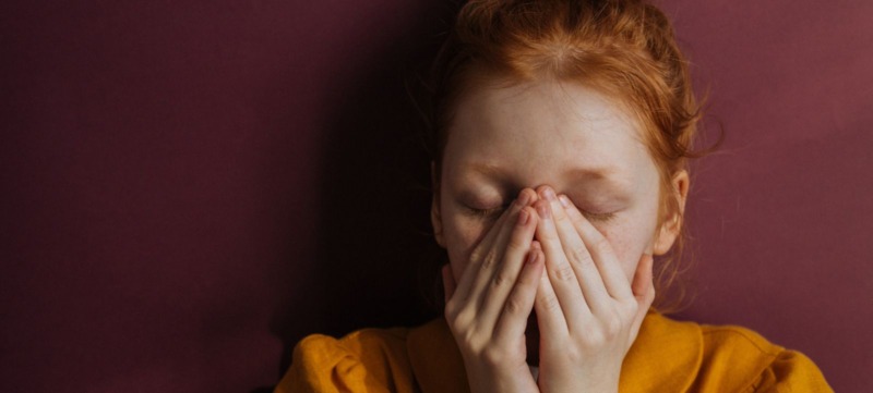 Vrouw met handen voor haar gezicht door angst