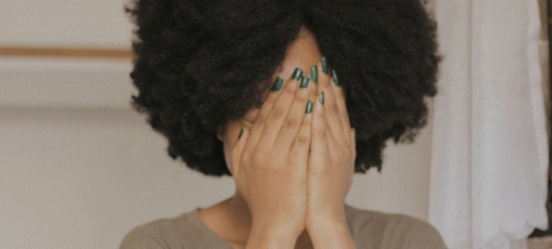 vrouw is verlegen en slaat haar handen voor haar hoofd