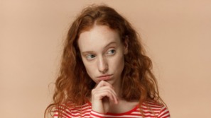 vrouw kijkt twijfelend weg omdat ze het imposter syndroom heeft