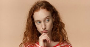 vrouw kijkt twijfelend weg omdat ze het imposter syndroom heeft