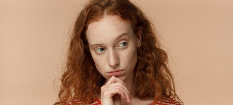 vrouw kijkt twijfelend weg omdat ze het imposter syndroom heeft