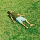 man ligt in het gras en doet waar hij zin in heeft