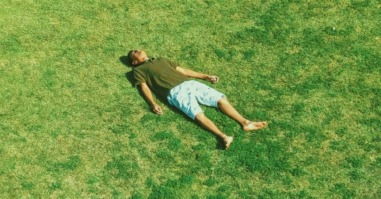 man ligt in het gras en doet waar hij zin in heeft
