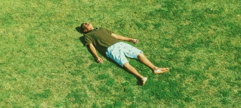 man ligt in het gras en doet waar hij zin in heeft
