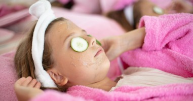 kind gebruikt skincare en ligt met maskertje op de bank