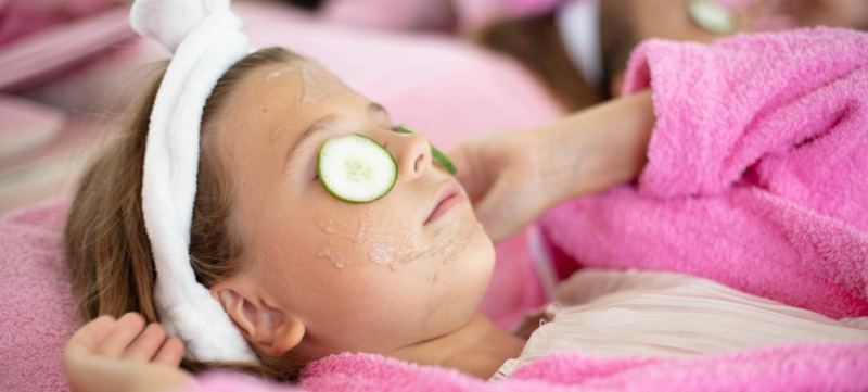 kind gebruikt skincare en ligt met maskertje op de bank