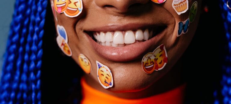 beeld van emoji's op gezicht van vrouw als beeld bij artikel over emoji-gebruik van mannen en vrouwen