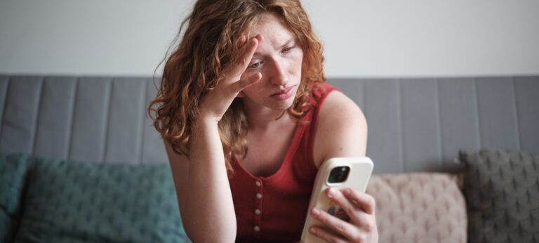 foto van een vrouw die fronsend naar haar telefoon kijkt ter illustratie bij een artikel over hypernormalisatie